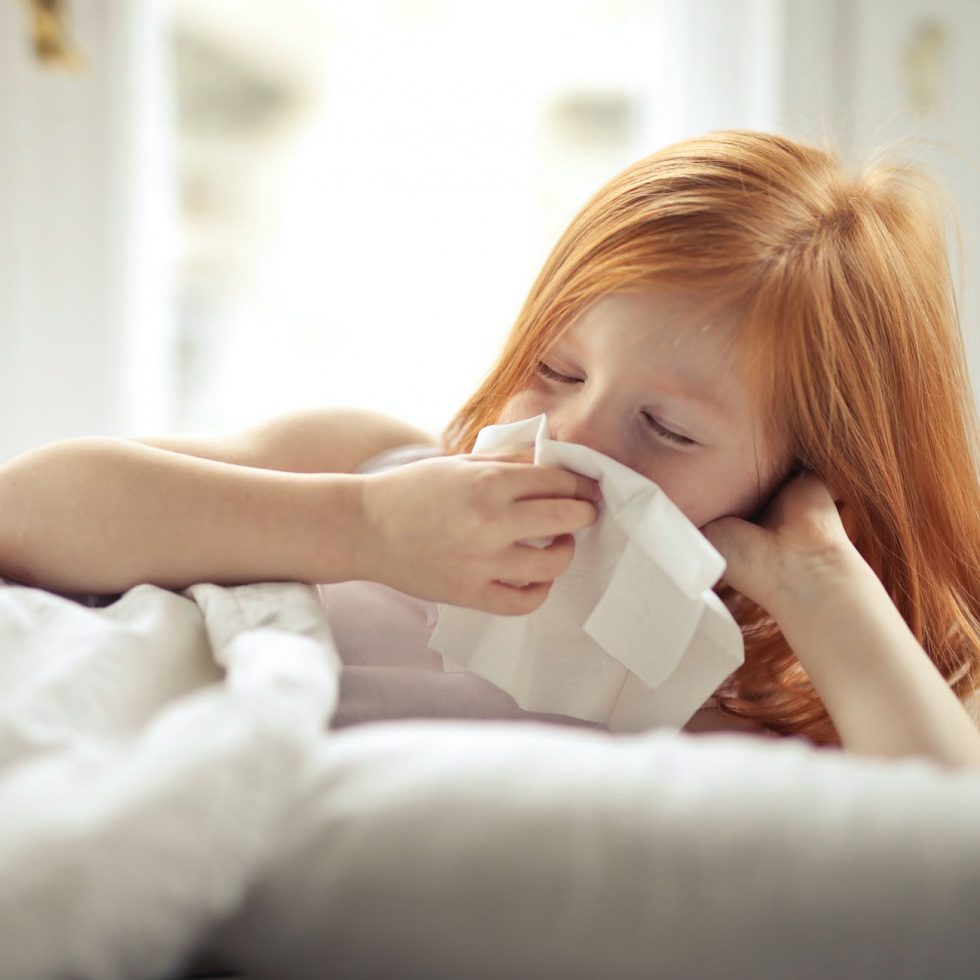 a sick girl wiping her nose with tissue